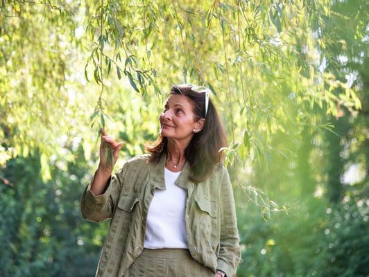Frühpensionierte Dame mit Sonnenbrille im Haar unter Weidenbaum
